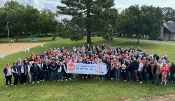 Ensemble des participants du congrès de la fédération CFDT Défense en juin 2025, tenant la bannière de l'événement, sur laquelle est inscrite : S'engager pour un monde plus juste.